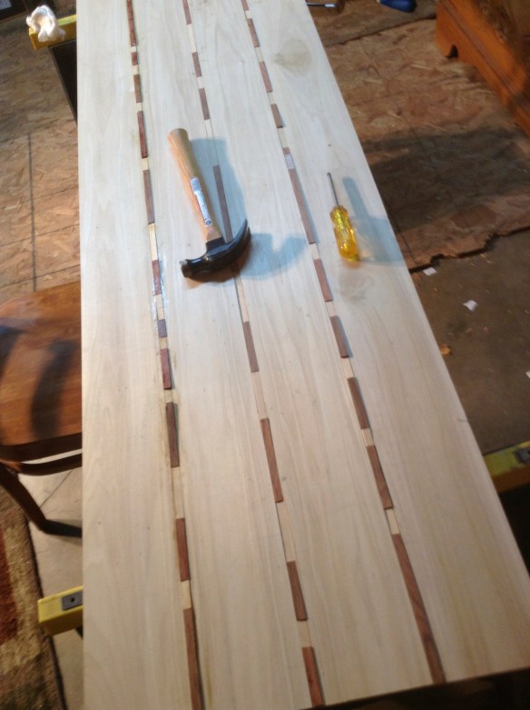 I poured glue in the groups and we placed the inlay pieces. I added too much glue to the first joint and made the mistake of wiping it when it was wet. I should have let it dry and chipped it off. Notice the inlay sticking up above the wood. I had to take my flush cutter and cut the excess off of each piece. That was a joy. I'll take better measurements next time.